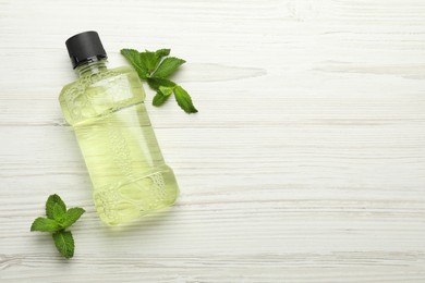 Photo of Mouthwash and mint on white wooden background, flat lay. Space for text