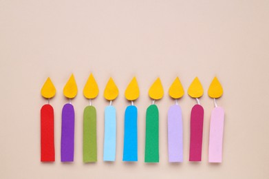 Different paper candles on beige background, flat lay