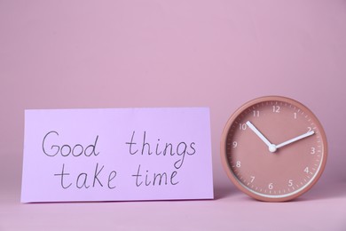 Photo of Card with phrase Good Things Take Time and clock on pink background. Motivational quote