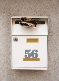 Metal mailbox with number 56 on stone wall outdoors