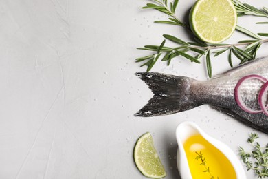 Flat lay composition with fresh raw dorado fish and ingredients on light grey table, space for text