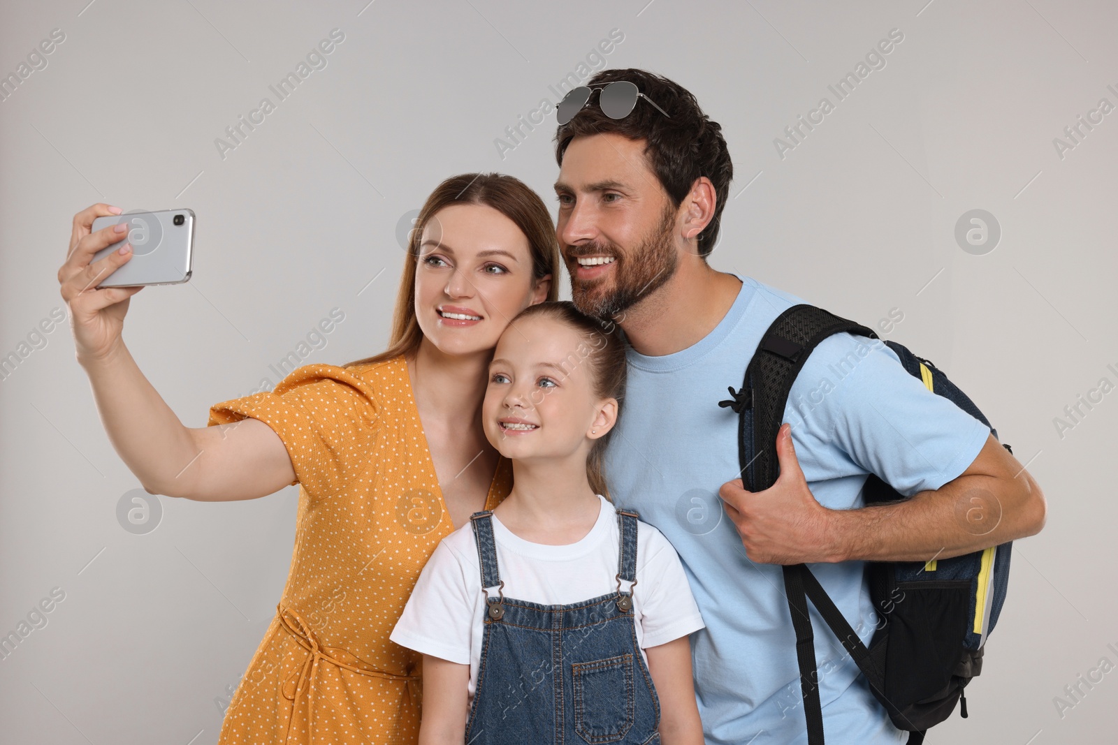 Photo of Happy family taking selfie on light grey background