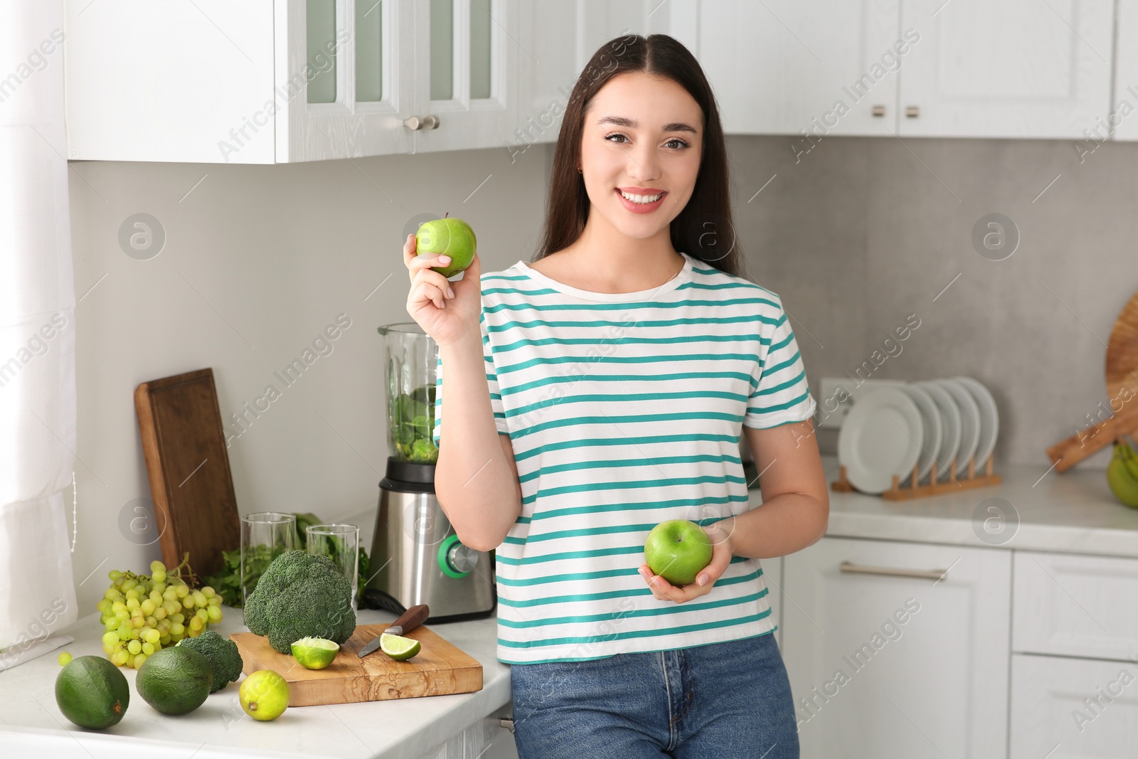 Photo of Beautiful young woman with apples for smoothie in kitchen