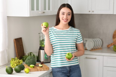 Beautiful young woman with apples for smoothie in kitchen