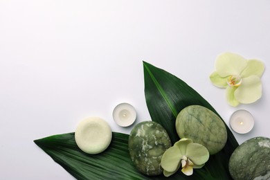 Photo of Flat lay composition with spa stones, solid shampoo bar and beautiful flowers on white table. Space for text