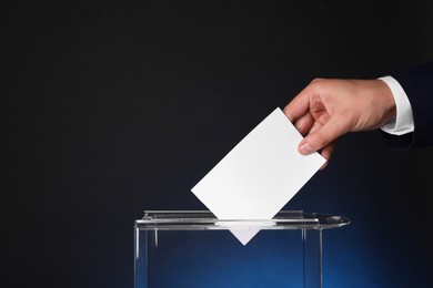 Photo of Man putting his vote into ballot box on dark blue background, closeup. Space for text