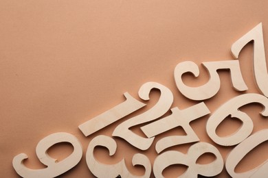 Wooden numbers on beige background, flat lay. Space for text