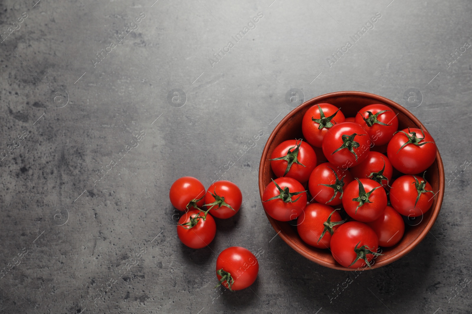 Photo of Bowl with ripe cherry tomatoes on color background, top view. Space for text