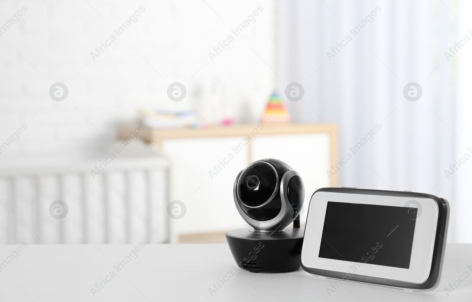 Photo of Baby monitor with camera on table in room, space for text. Video nanny