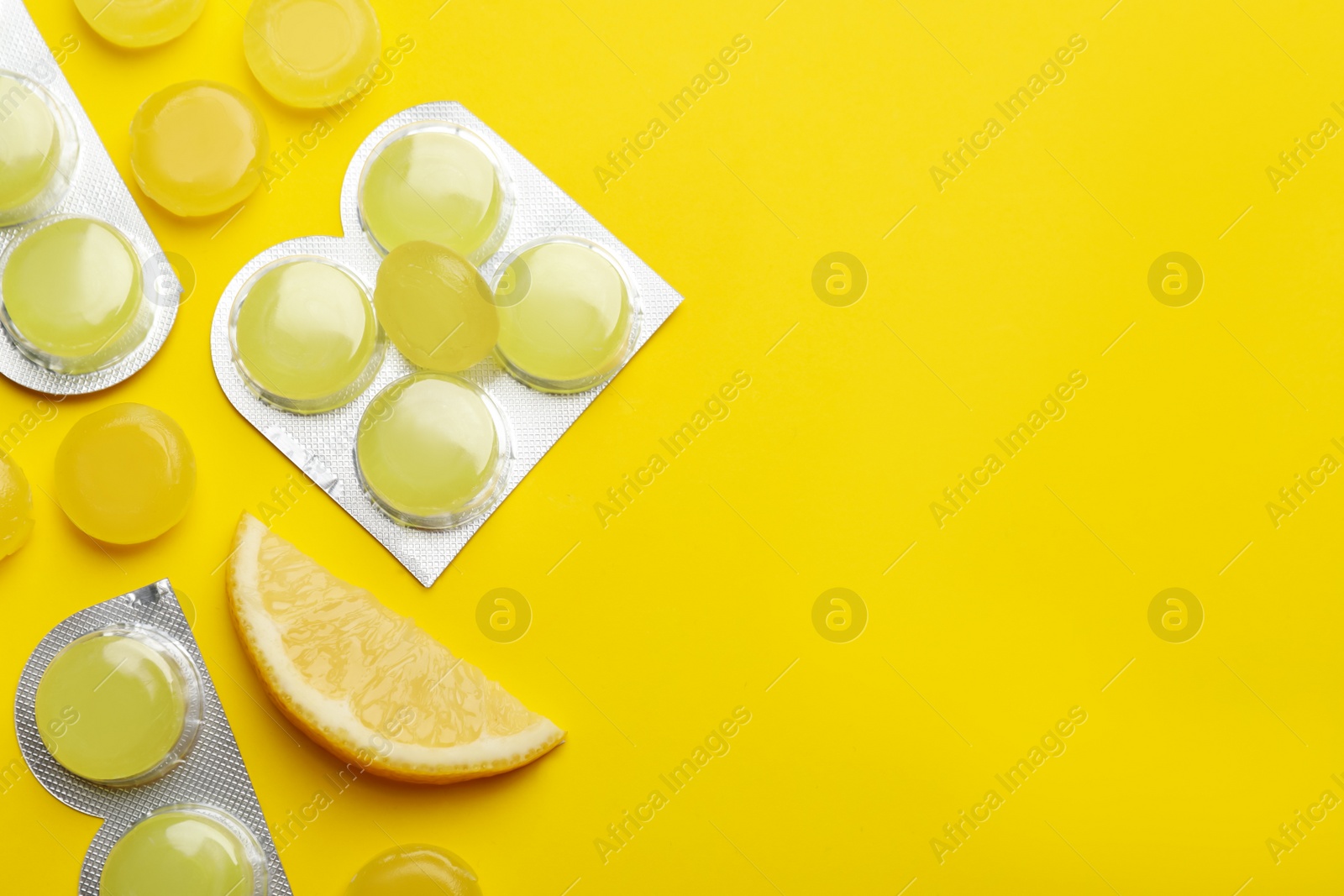 Photo of Many lemon cough drops on yellow background, flat lay. Space for text