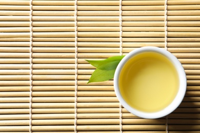 Cup of freshly brewed oolong tea on bamboo mat, top view with space for text