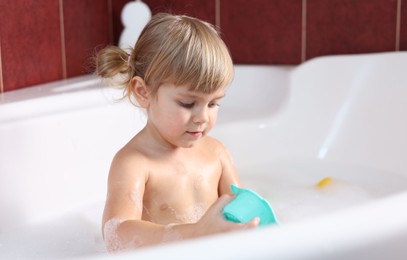 Little girl bathing in tub at home