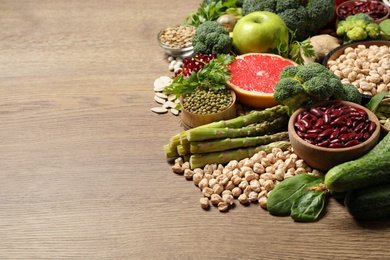 Photo of Fresh vegetables, fruits and seeds on wooden table, space for text