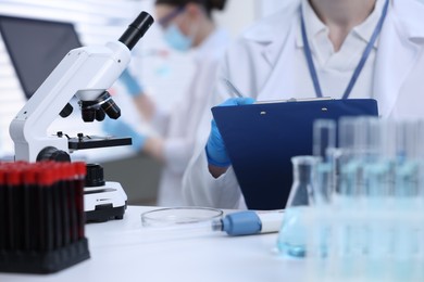 Photo of Scientist working with laboratory test form at table indoors, closeup