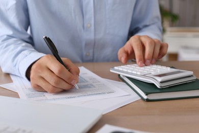 Photo of Tax accountant with calculator working at table in office, closeup