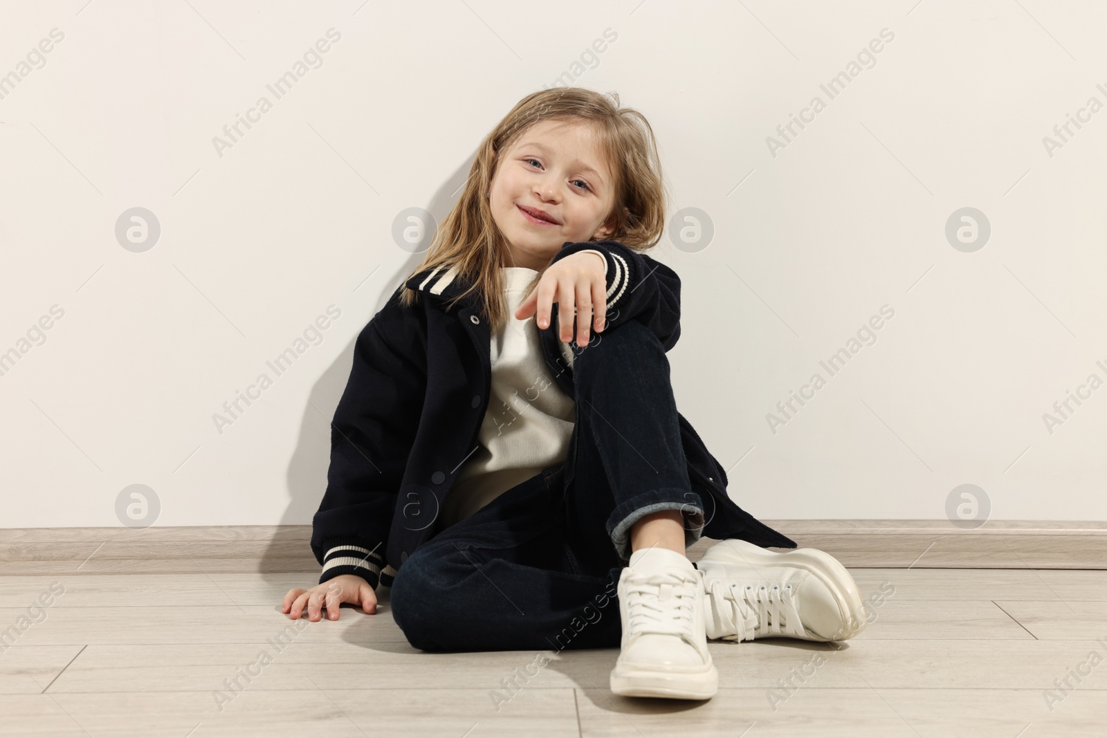 Photo of Fashion concept. Stylish girl sitting near white wall