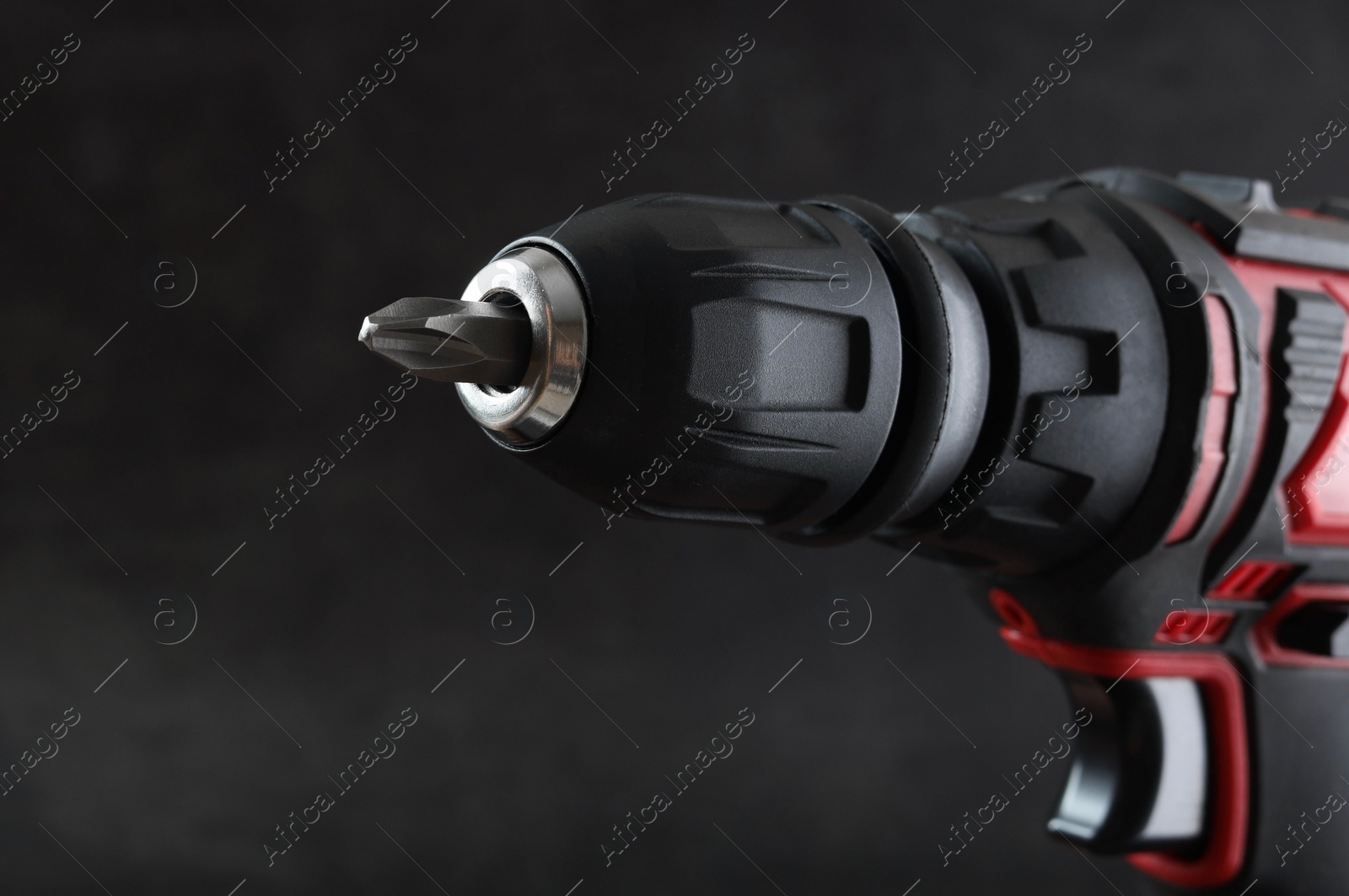 Photo of Modern electric screwdriver on dark grey background, closeup. Space for text