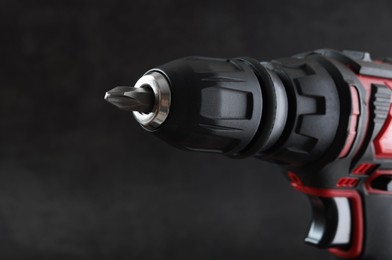 Photo of Modern electric screwdriver on dark grey background, closeup. Space for text