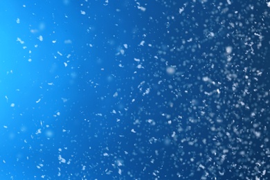 Photo of Snow flakes falling on blue background. Winter weather