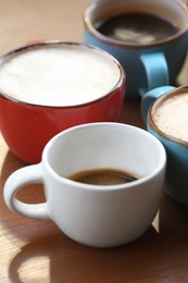 Photo of Cups of fresh aromatic coffee on wooden table, closeup