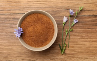 Photo of Bowl of chicory powder and flowers on wooden table, flat lay