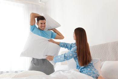 Happy couple having pillow fight in bedroom