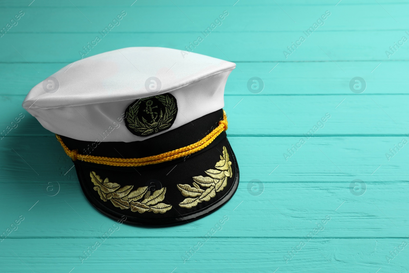 Photo of Peaked cap with accessories on turquoise wooden background, space for text