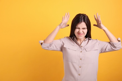 Portrait of stressed young woman on yellow background. Space for text