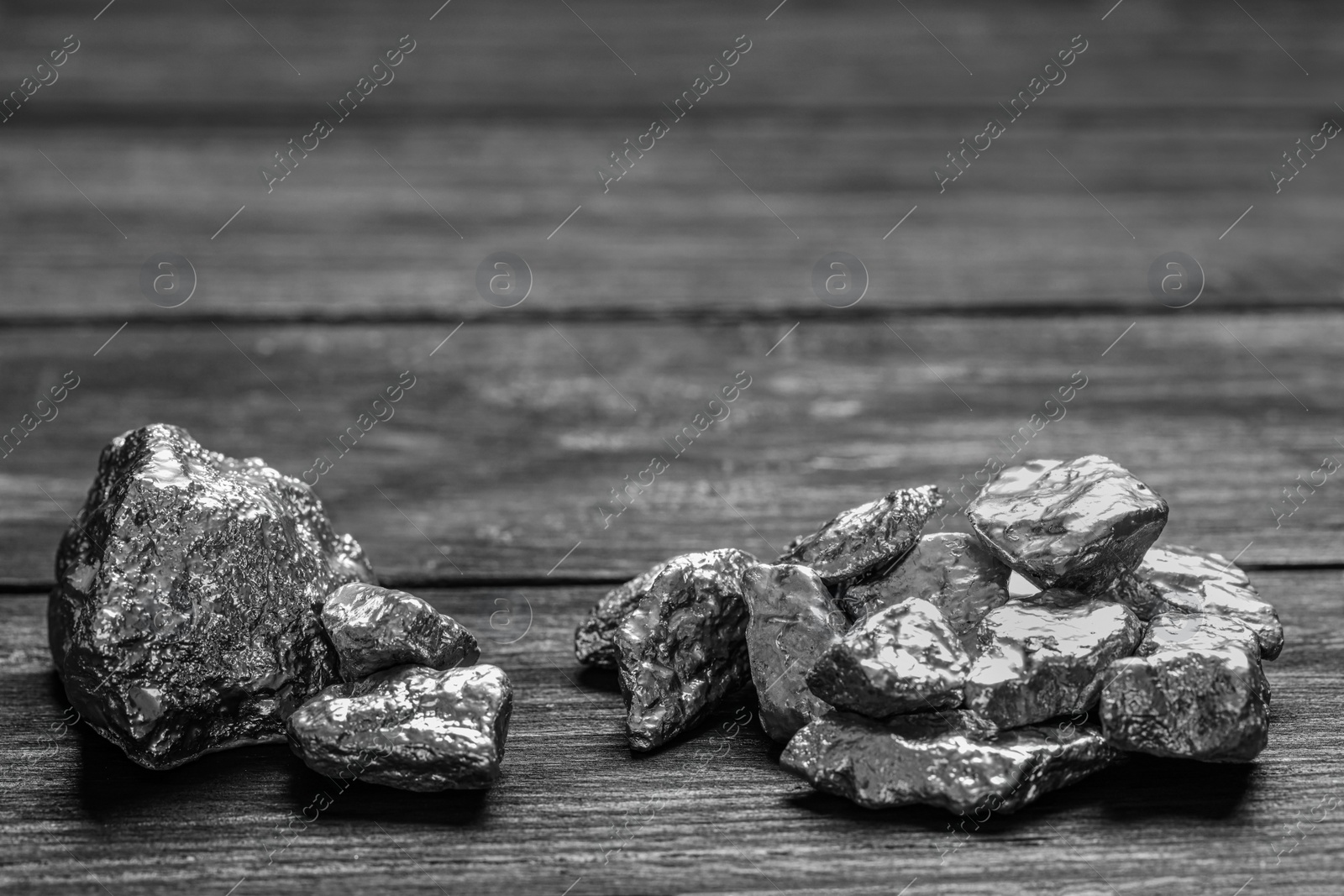 Photo of Pile of silver nuggets on black wooden table. Space for text