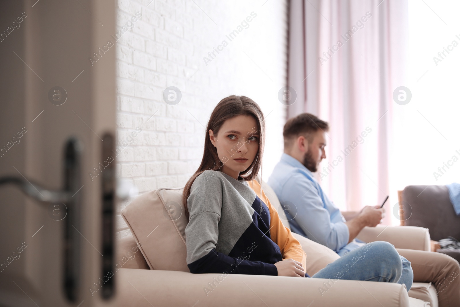 Photo of Young man preferring smartphone over his girlfriend at home. Relationship problems