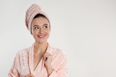 Photo of Beautiful young woman in bathrobe on light background. Space for text