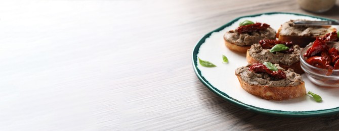 Image of Slices of bread with delicious pate, sun dried tomatoes and basil on wooden table, space for text. Banner design