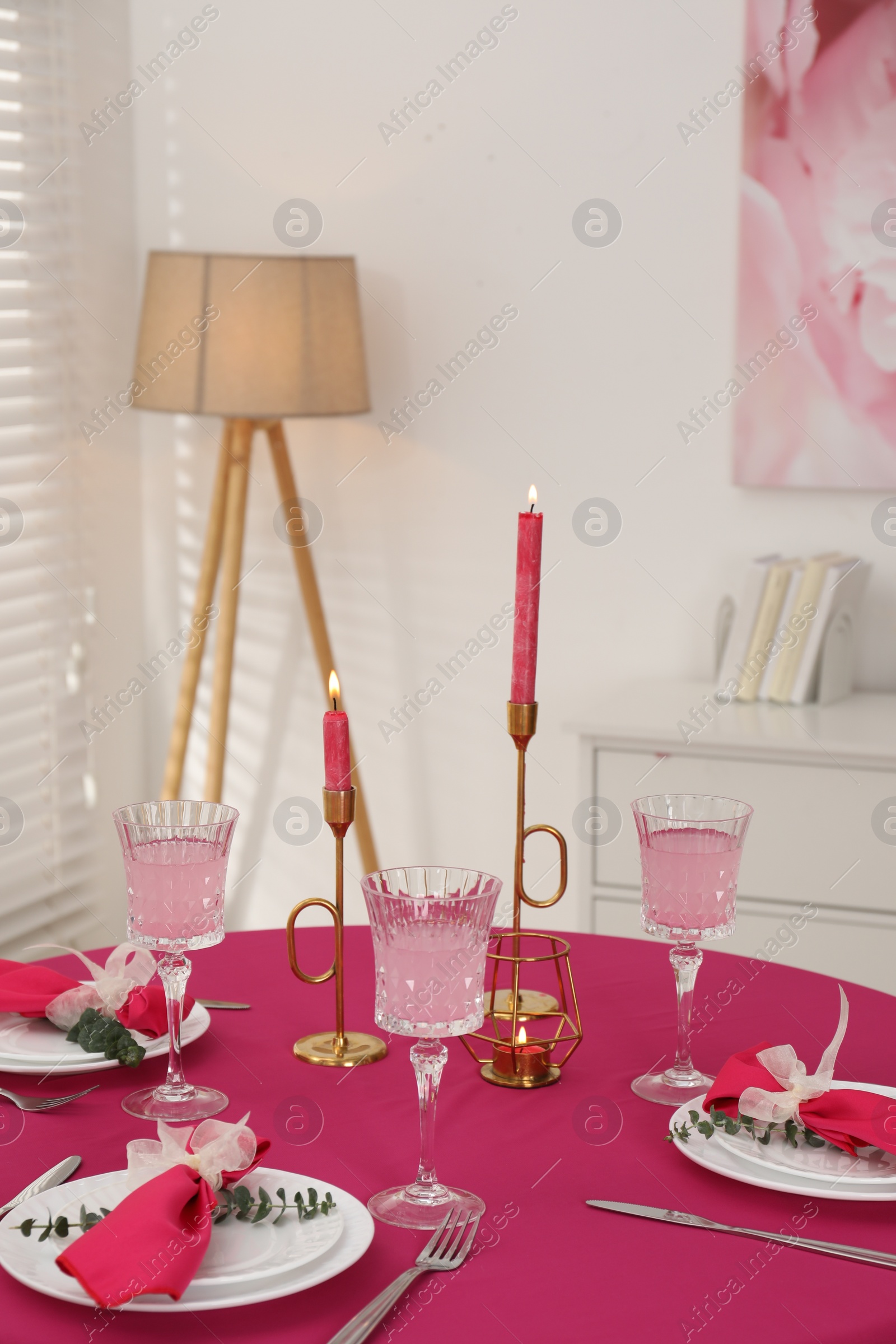 Photo of Beautiful table setting with green branches and burning candles in dining room