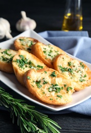 Plate with delicious homemade garlic bread on table