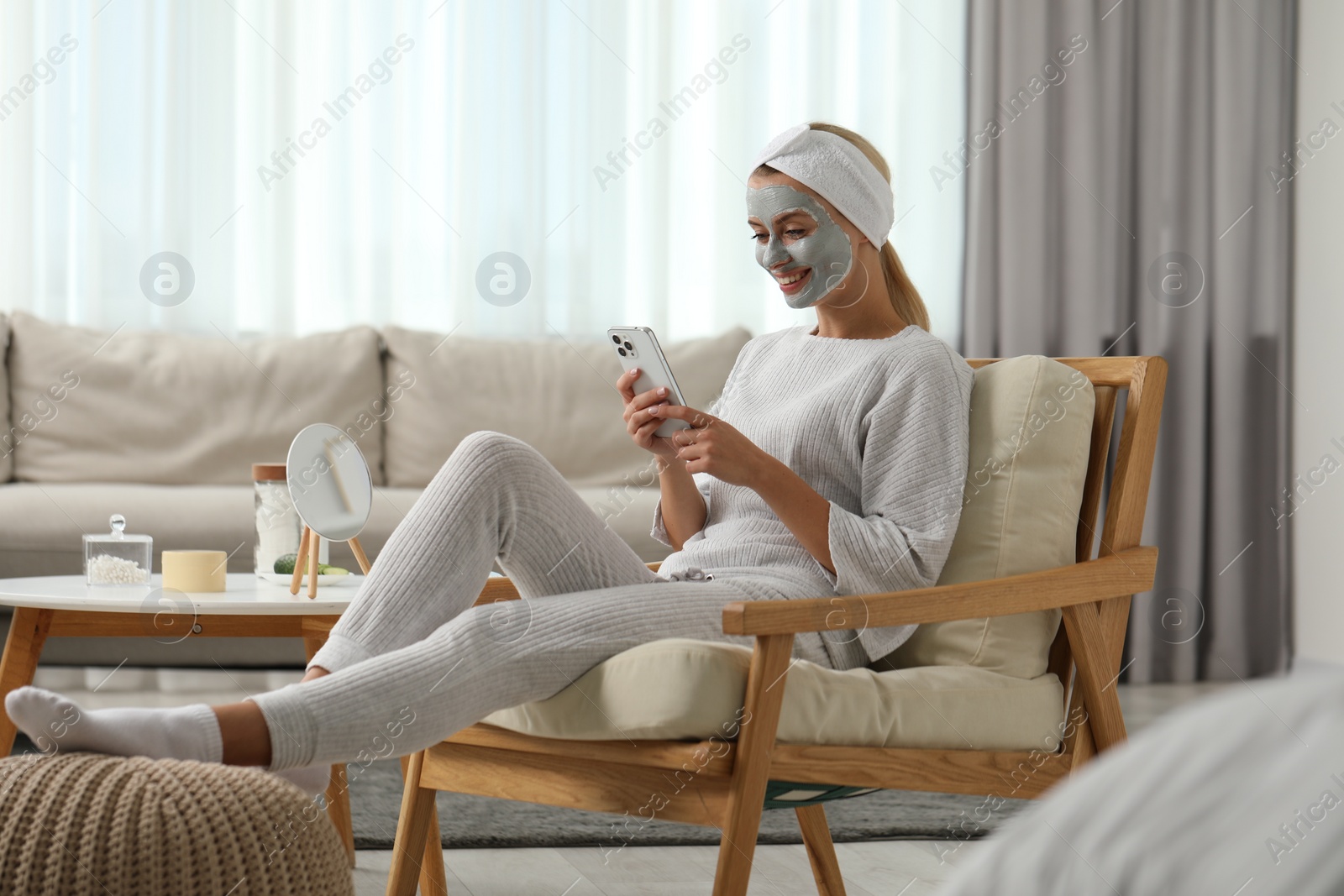 Photo of Young woman with face mask using smartphone at home, space for text. Spa treatments