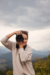 Photo of Professional photographer taking picture with modern camera in mountains