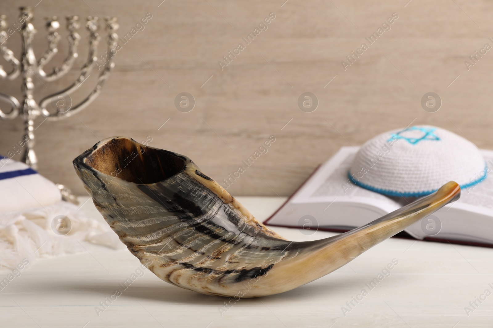 Photo of Shofar, Torah and kippah with Star of David on white wooden table. Rosh Hashanah holiday symbols