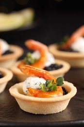 Delicious canapes with shrimps and black caviar on table, closeup