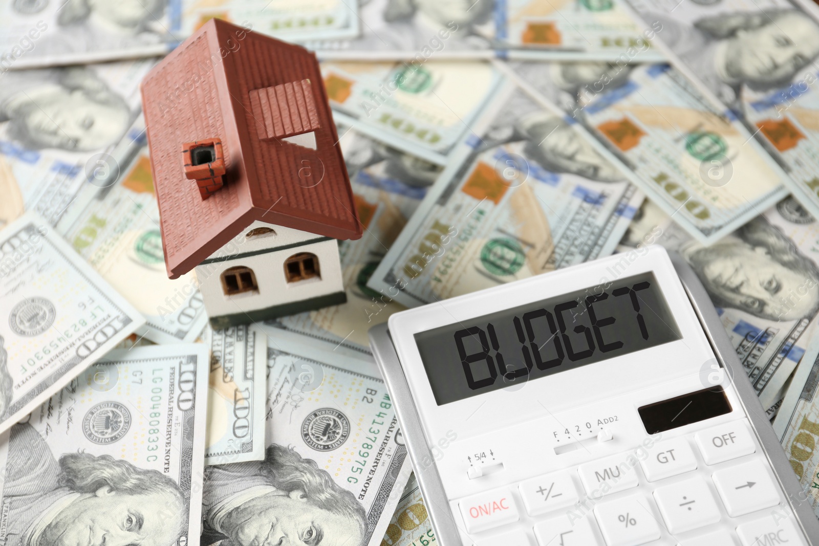 Image of Budget plan. Calculator and house model on dollar banknotes