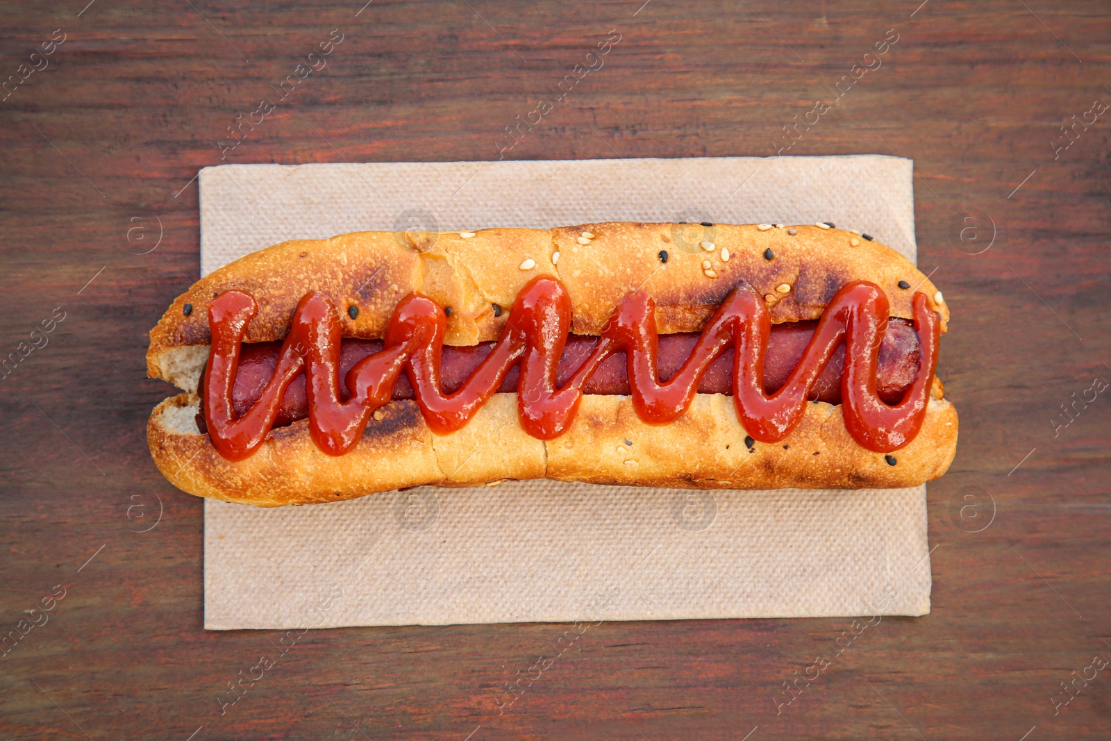 Photo of Fresh tasty hot dog with ketchup on wooden table, top view