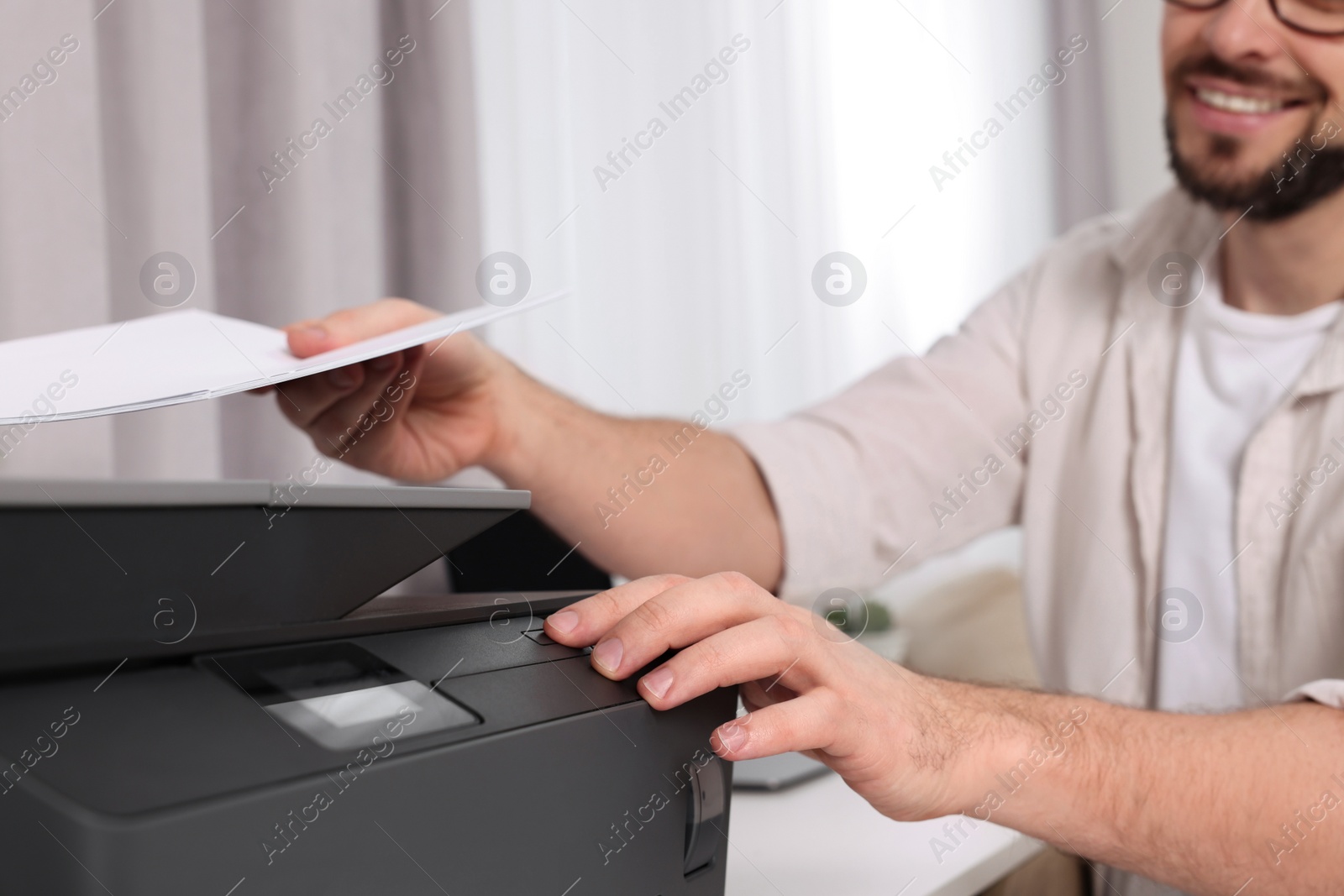 Photo of Man using modern printer at workplace indoors, closeup