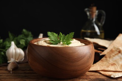 Photo of Delicious hummus and pita chips on wooden table, closeup