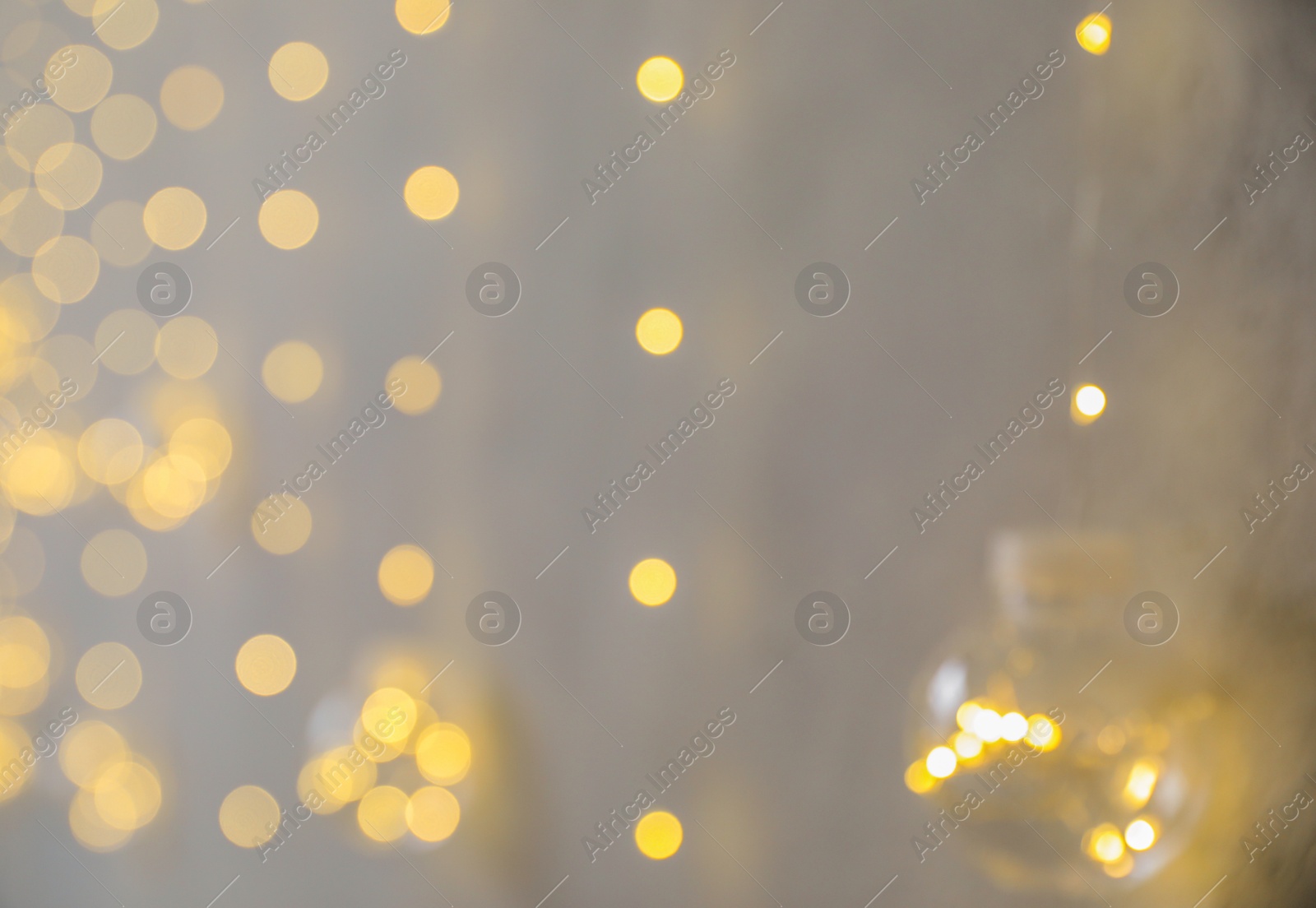 Photo of Blurred view of Christmas fairy lights on grey wall. Interior decoration