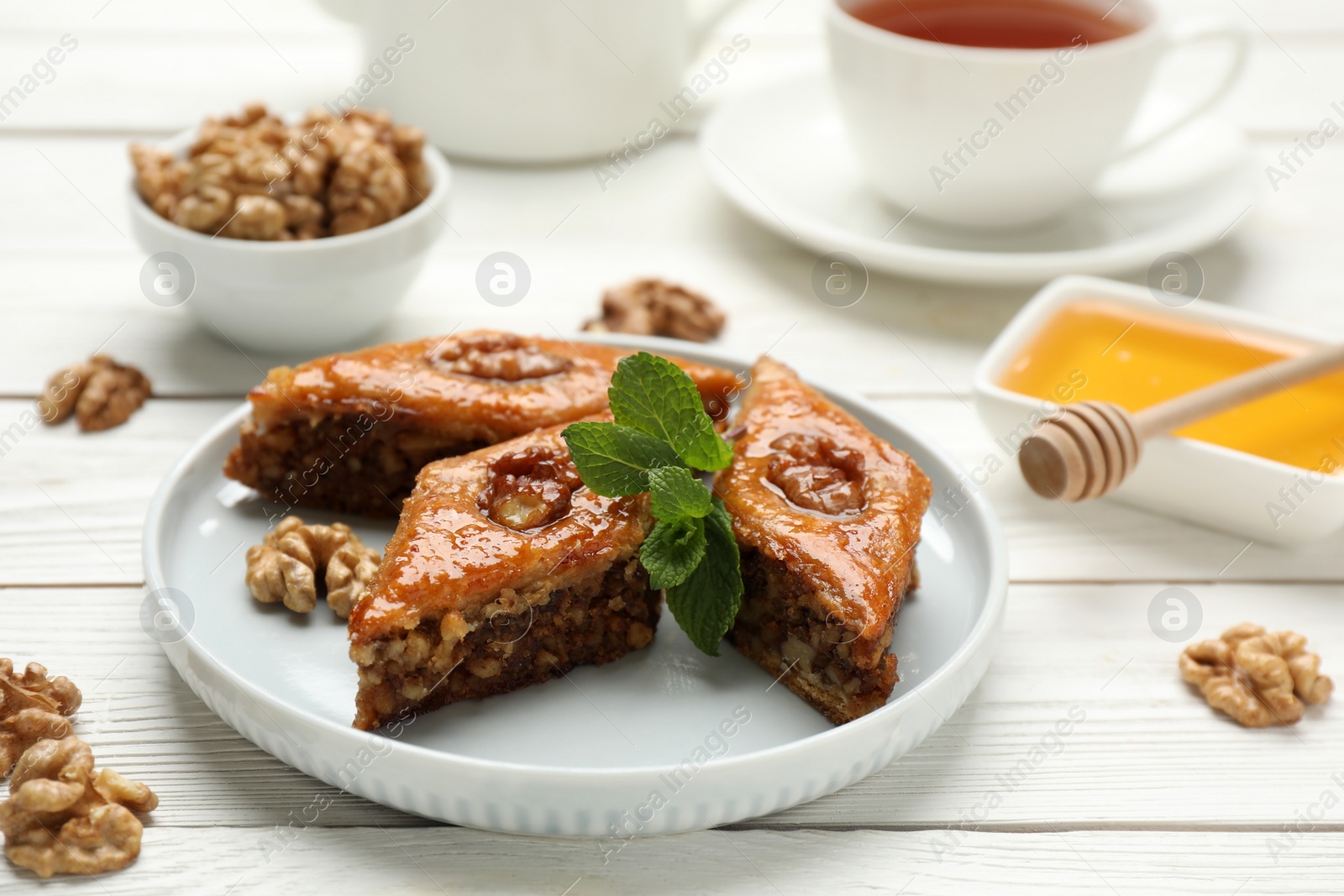 Photo of Delicious sweet baklava with walnuts and mint on white wooden table