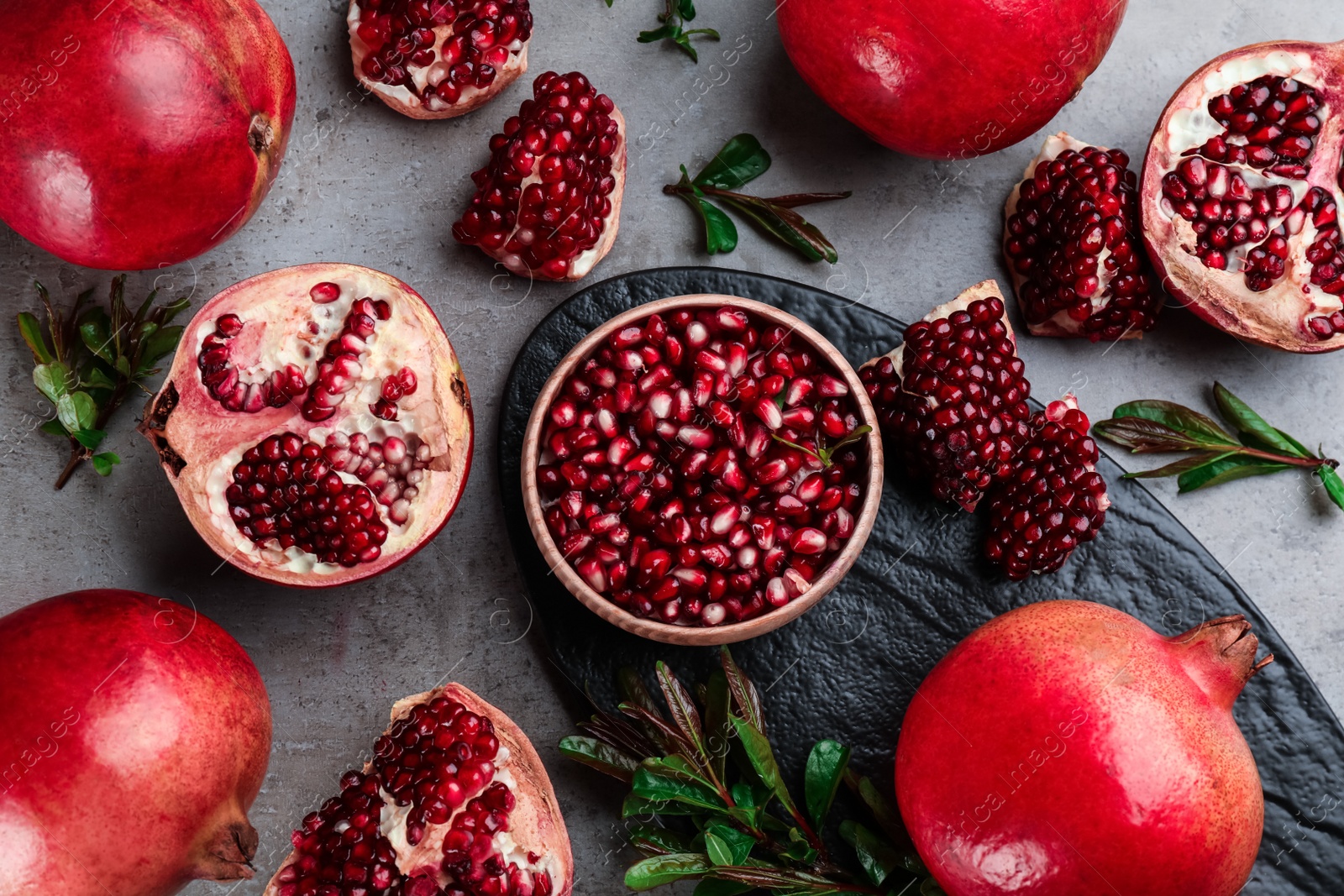 Photo of Delicious ripe pomegranates on grey table, flat lay