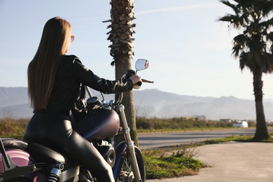 Beautiful woman riding motorcycle on sunny day, back view