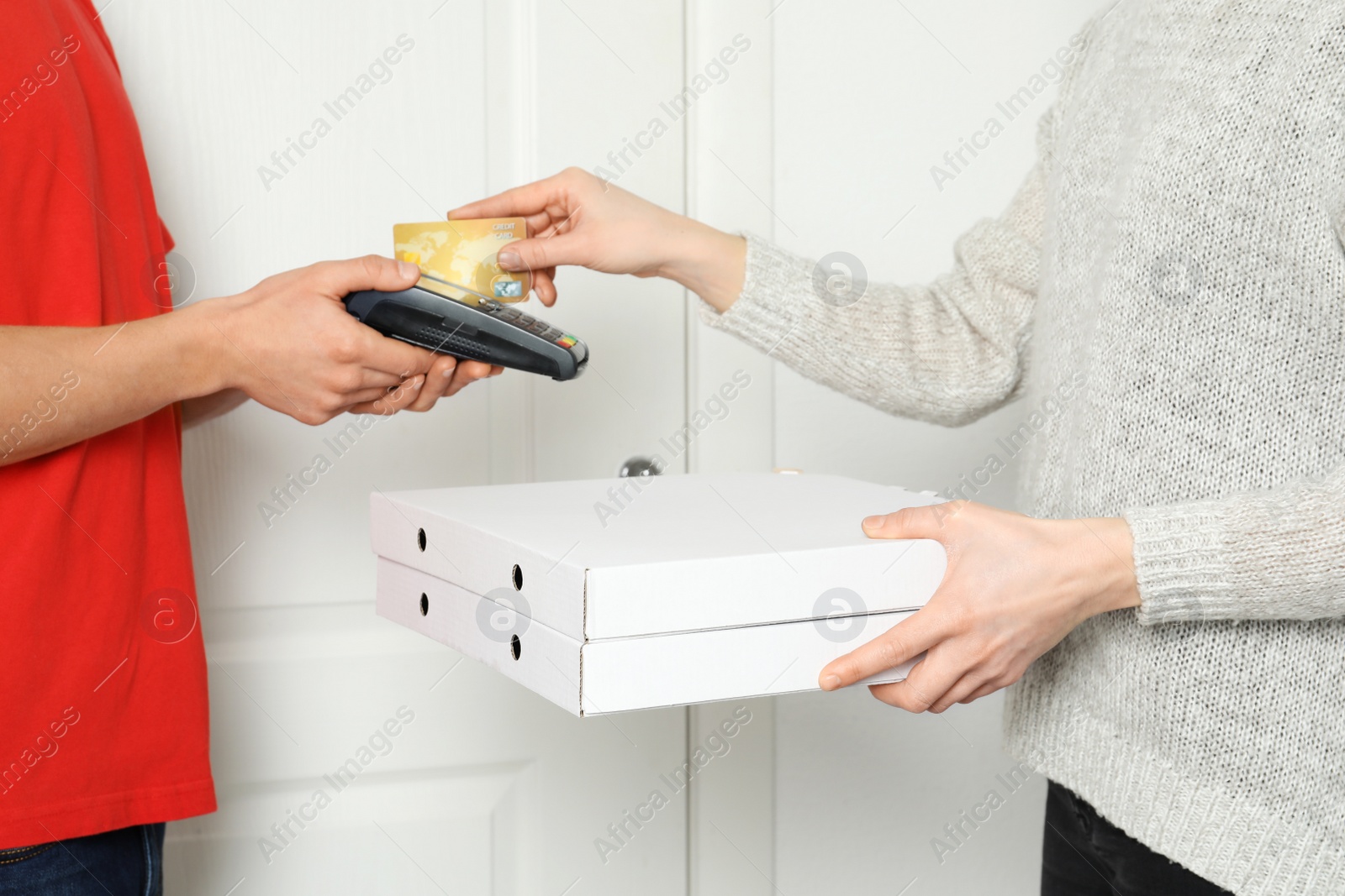 Photo of Young woman using bank terminal to pay for food delivery at doorway, closeup. Ordering pizza