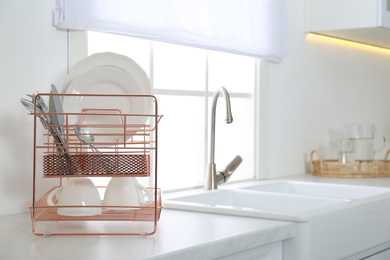 Clean dishes on drying rack in modern kitchen interior