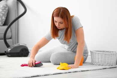 Photo of Tired housewife cleaning carpet at home