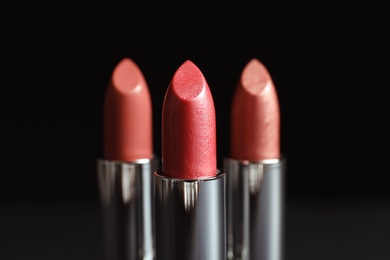 Photo of Different lipsticks on dark background. Cosmetic product